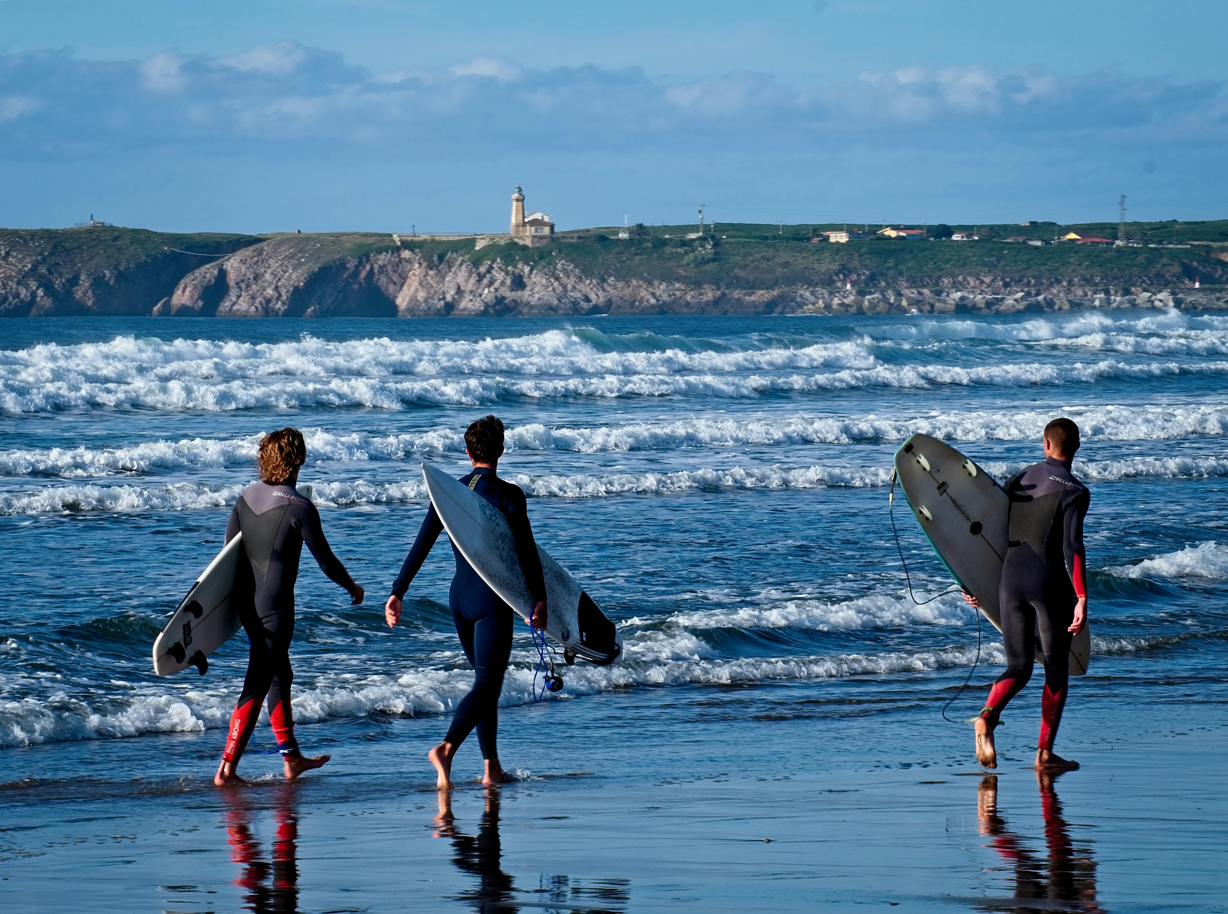 man and woman holding surfboard walking on beach during daytime